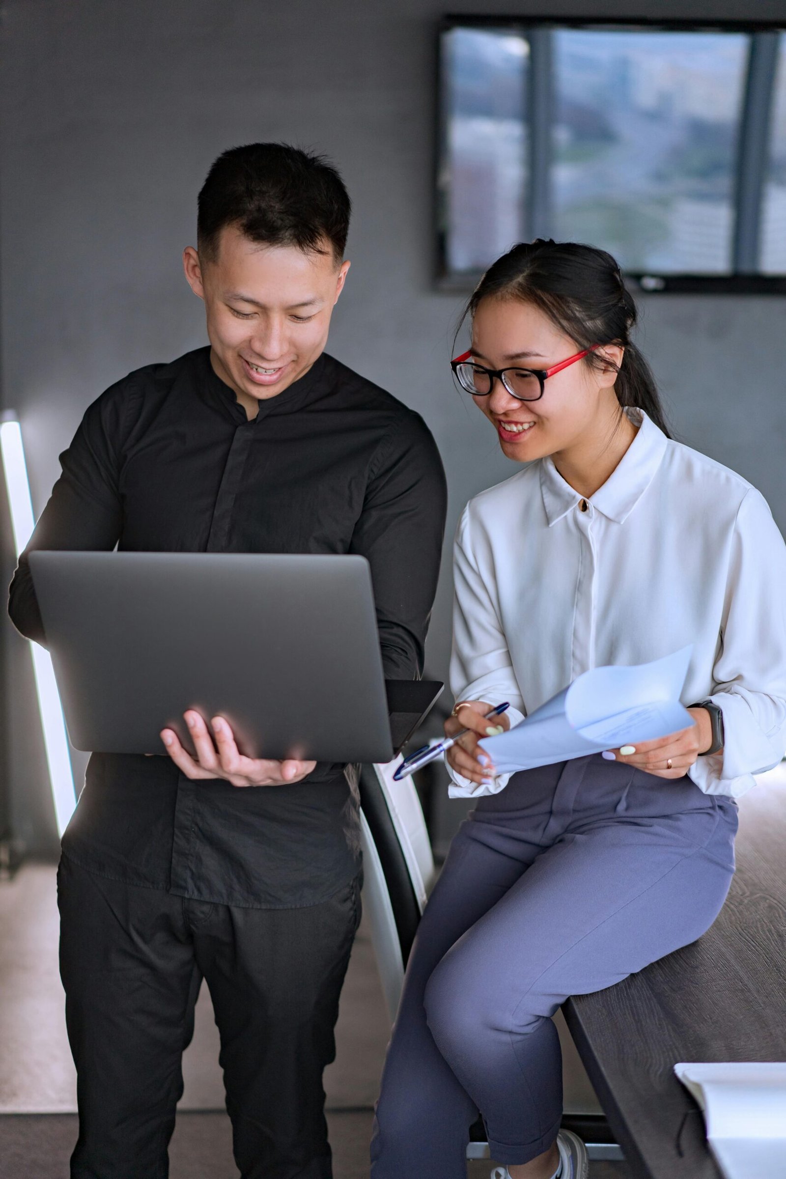 Two young professionals collaborating on a project in a modern office space.